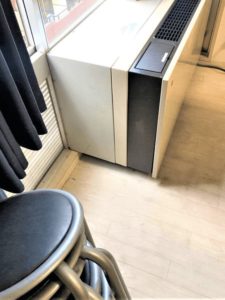 白い床置き型エアコンと丸形パイプ椅子